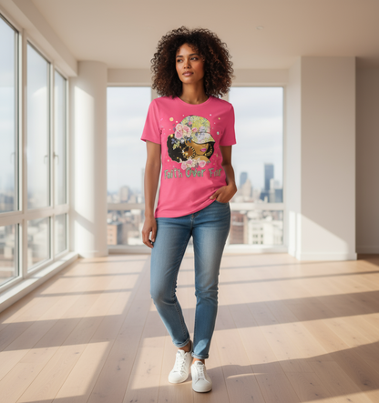 Woman wearing a pink t-shirt with a graphic design, standing in a modern room with large windows.